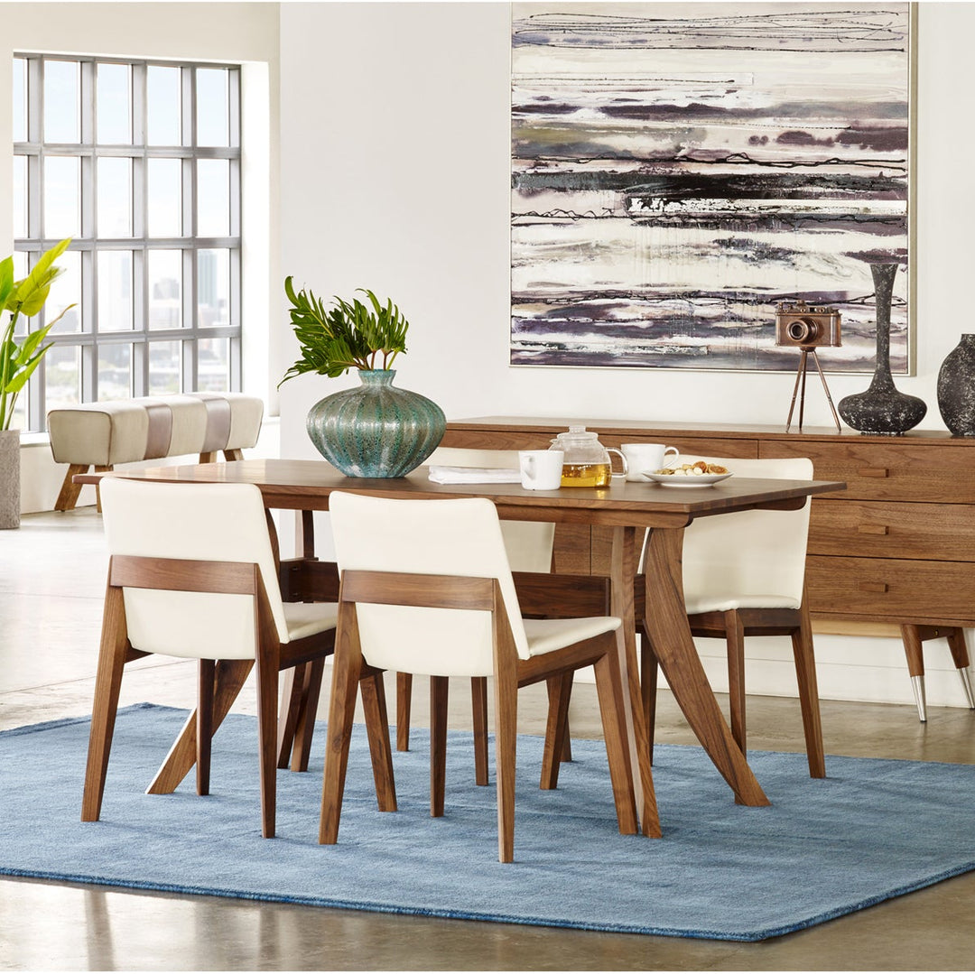 Dining room with wooden table and chairs, abstract painting, and decorative items.