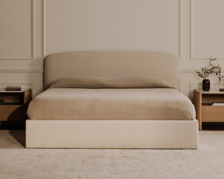 Beige bed with matching nightstands in a room with beige walls and carpet.