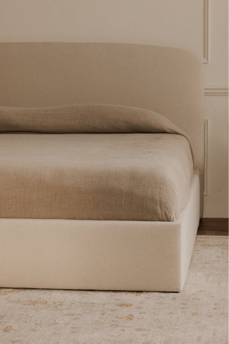 Beige bed with matching headboard against a beige wall.
