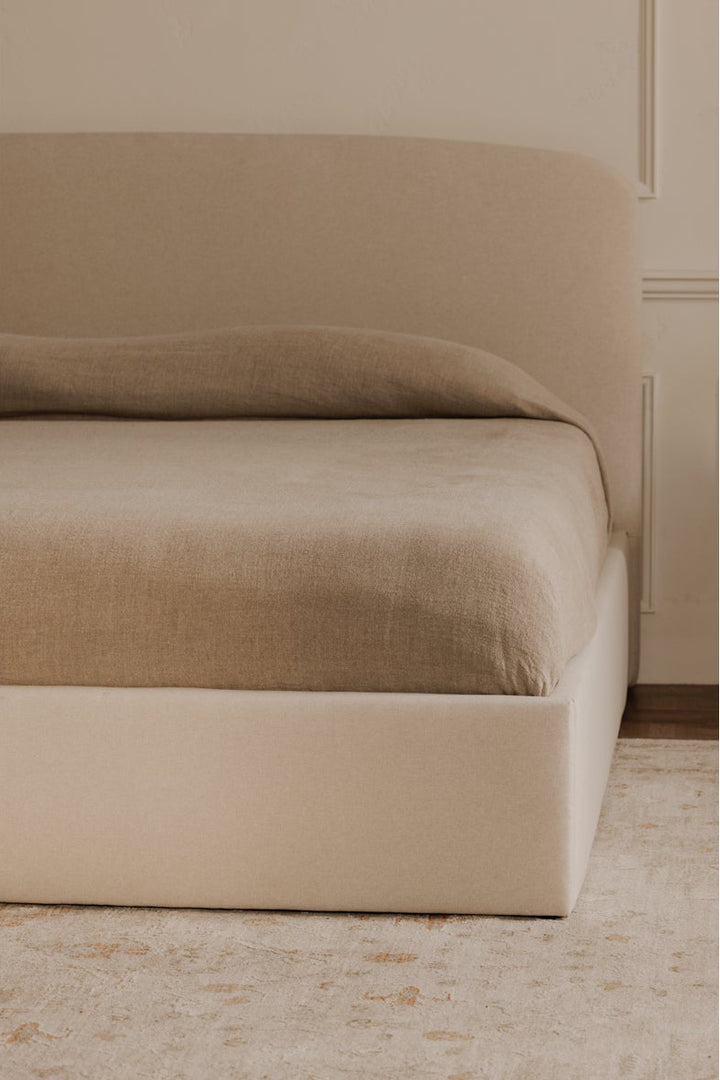 Beige bed with matching headboard against a beige wall.