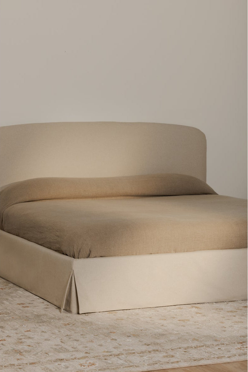 Beige bed with a wooden floor and neutral wall