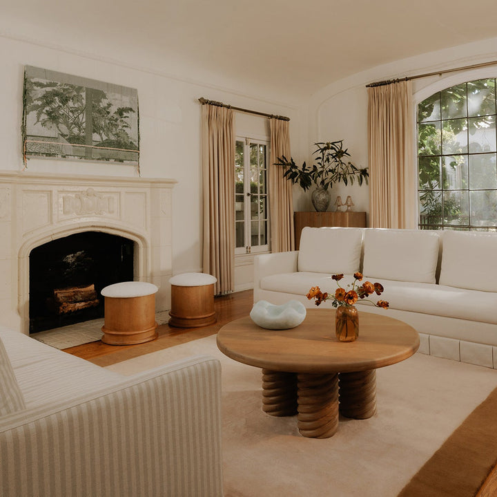 Living room with white sofas, a wooden coffee table, and a fireplace.