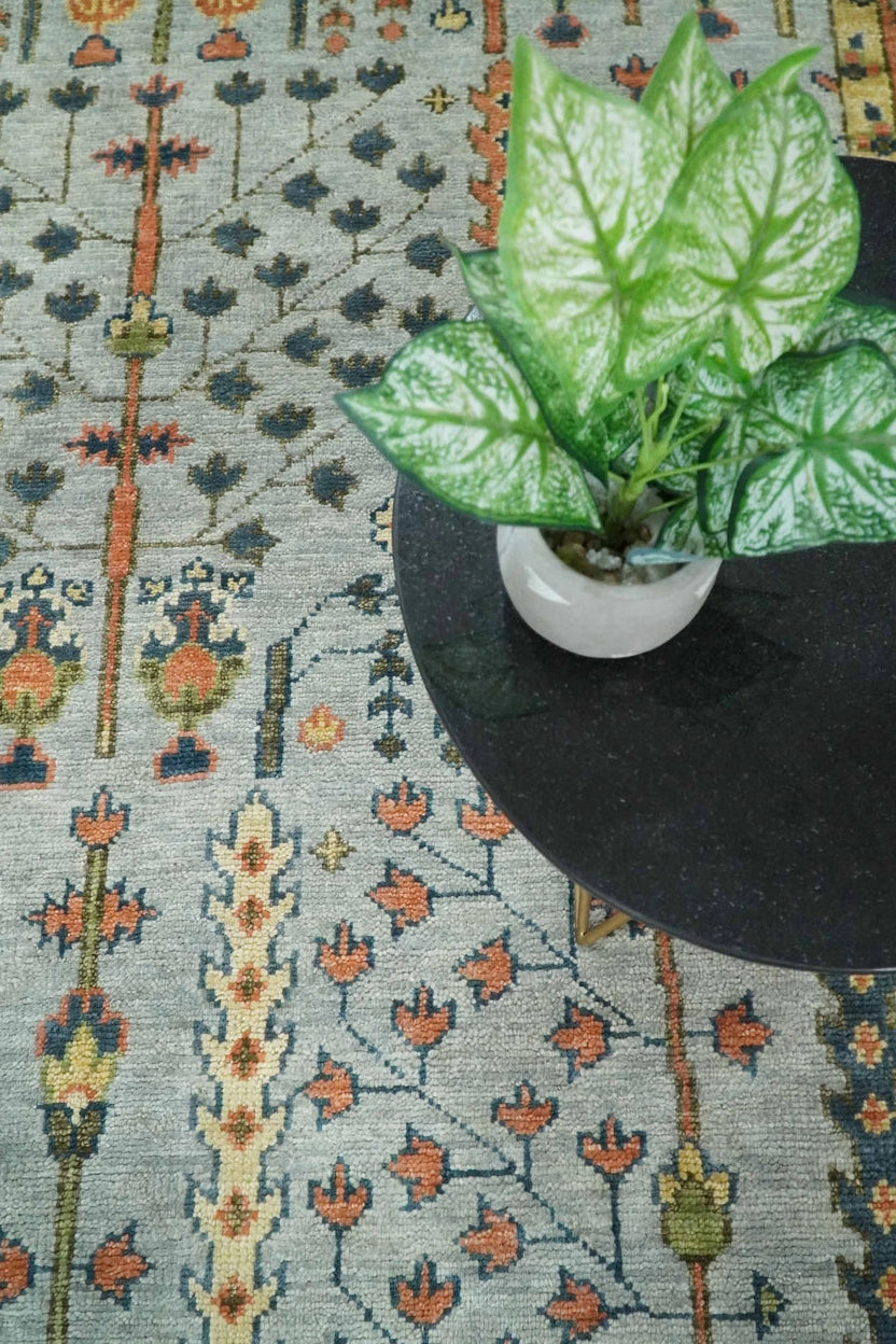 Decorative rug with floral pattern and a potted plant on a table.
